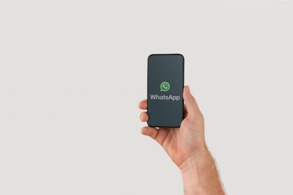 Tangan memegang handphone dengan logo WhatsApp